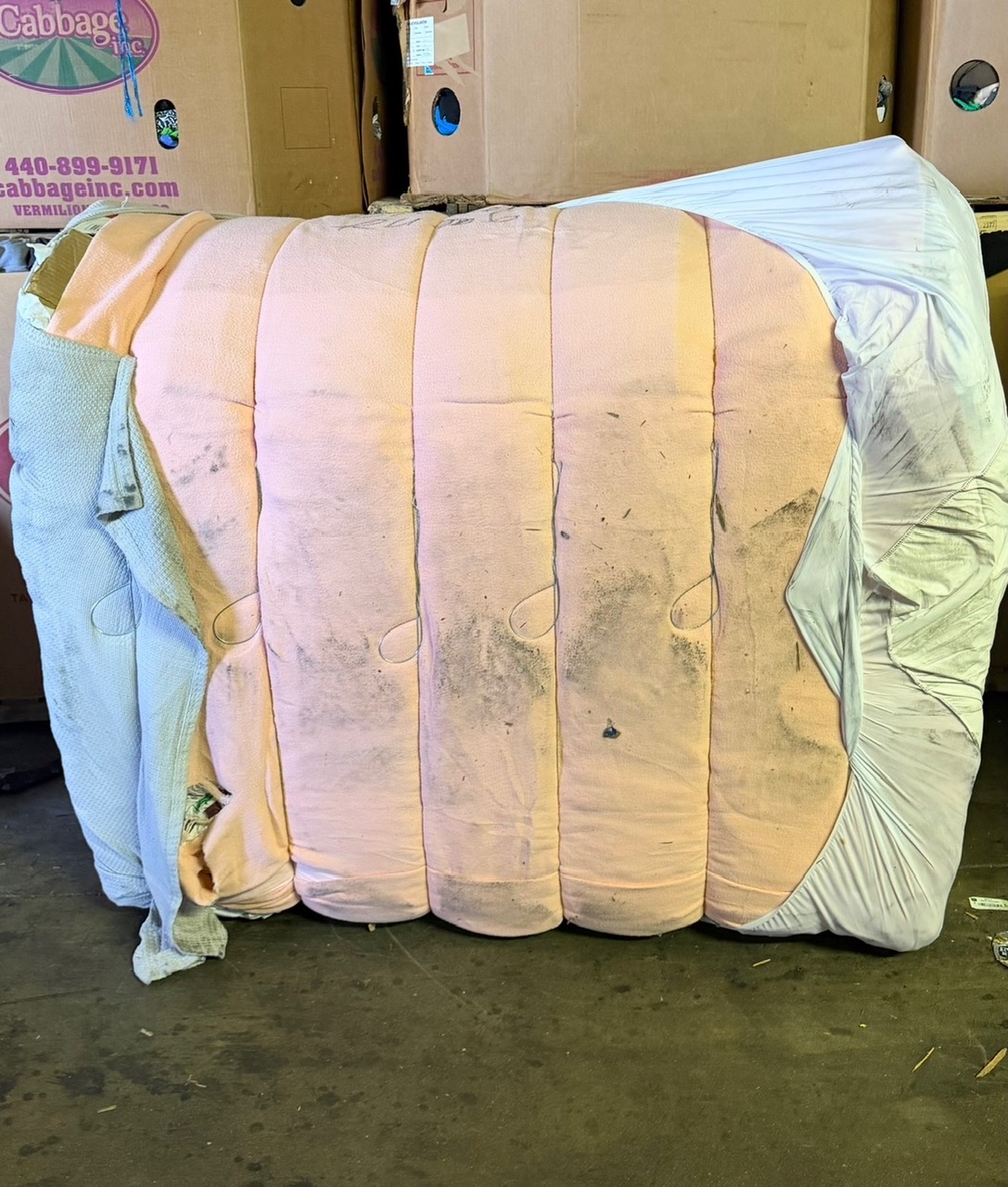A compressed, strapped bale of raw credential clothing and linens