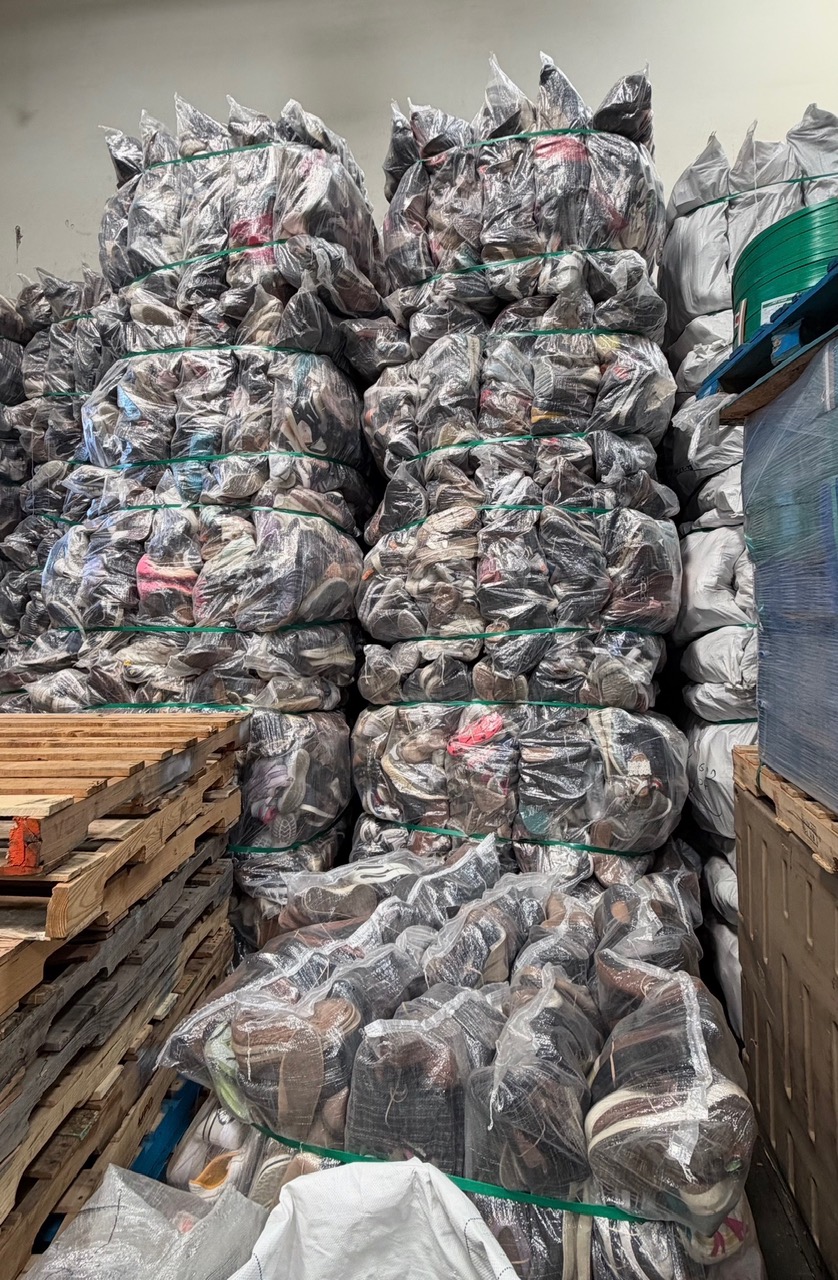 Stacks of clear-wrapped, strapped bales of credential shoes in a warehouse